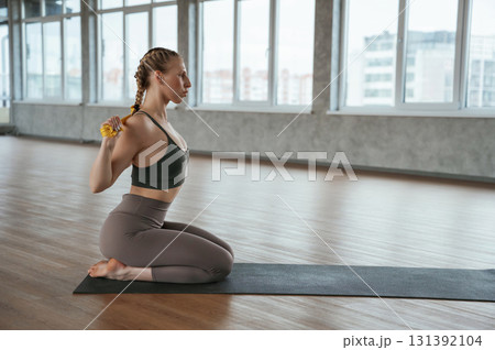 Doing stretches by using strap. Fitness woman in sportswear is indoors Doing stretches by using strap. Fitness woman in sportswear is indoors 131392104