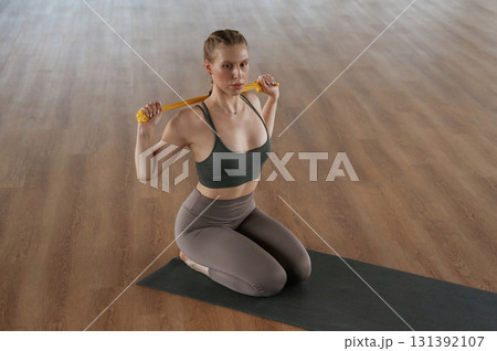 Doing stretches by using strap. Fitness woman in sportswear is indoors Doing stretches by using strap. Fitness woman in sportswear is indoors 131392107