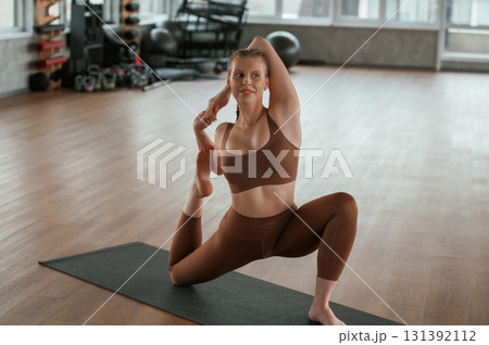 Front view. Warm up exercises. Fitness woman in sportswear is indoors 131392112