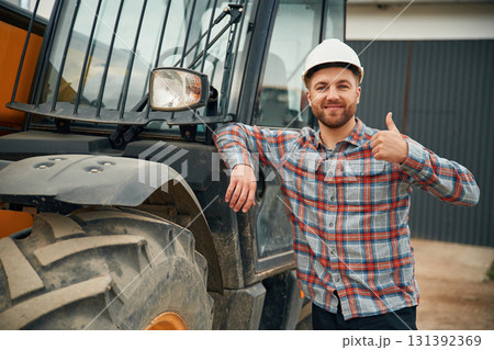 Leaning on the vehicle. Man is with tractor. Agricultural worker Leaning on the vehicle. Man is with tractor. Agricultural worker 131392369