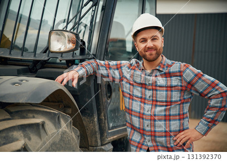 Leaning on the vehicle. Man is with tractor. Agricultural worker Leaning on the vehicle. Man is with tractor. Agricultural worker 131392370