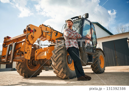 With arms crossed. Man is with tractor. Agricultural worker 131392386