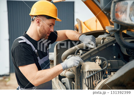 Doing maintenance. Man is with tractor. Agricultural worker 131392399