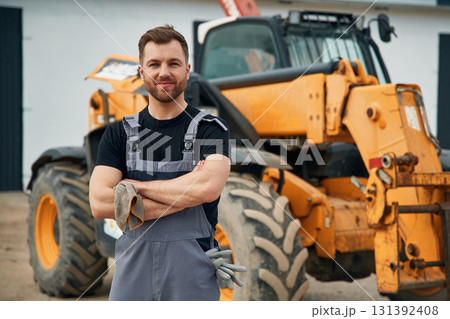 With arms crossed. Man is with tractor. Agricultural worker 131392408