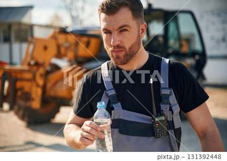 Drinking water, taking a break, tired. Man is with tractor. Agricultural worker Drinking water, taking a break, tired. Man is with tractor. Agricultural worker 131392448