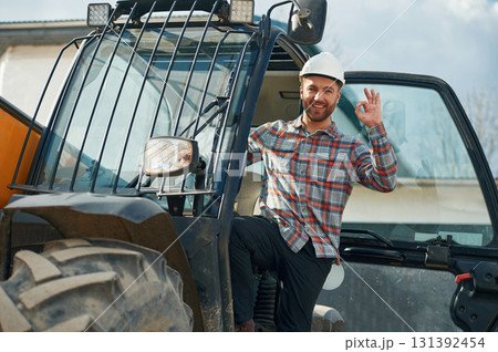 Happy driver. Man is with tractor. Agricultural worker Happy driver. Man is with tractor. Agricultural worker 131392454