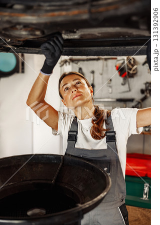 A skilled female mechanic is performing essential maintenance tasks in a busy workshop A skilled female mechanic is performing essential maintenance tasks in a busy workshop 131392906