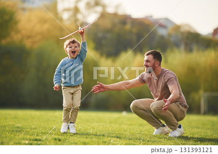 Weekend activities. Playing with toy plane. Happy father with son are having fun on the field at summertime 131393121