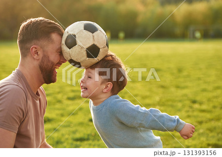 Positive emotions, holding soccer ball by heads. Happy father with son are having fun on the field at summertime 131393156