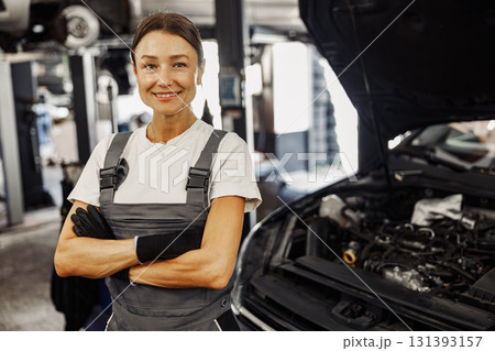 A female mechanic proudly works in an auto shop, symbolizing confidence and empowerment A female mechanic proudly works in an auto shop, symbolizing confidence and empowerment 131393157