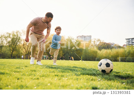 Playing soccer. Happy father with son are having fun on the field at summertime Playing soccer. Happy father with son are having fun on the field at summertime 131393381