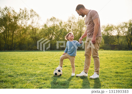 Game of soccer. With ball. Happy father with son are having fun on the field at summertime 131393383