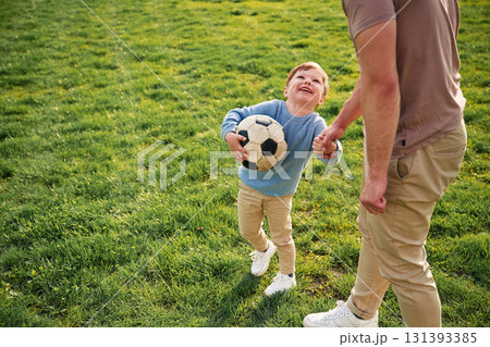 Game of soccer. With ball. Happy father with son are having fun on the field at summertime Game of soccer. With ball. Happy father with son are having fun on the field at summertime 131393385