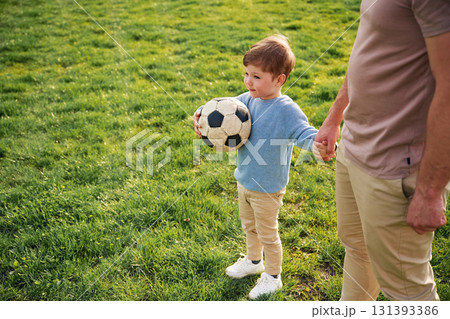 Game of soccer. With ball. Happy father with son are having fun on the field at summertime Game of soccer. With ball. Happy father with son are having fun on the field at summertime 131393386