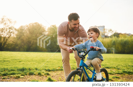 With bicycle, having fun. Happy father with son are on the field at summertime 131393424