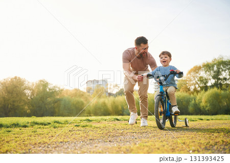 Bicycle, having fun. Happy father with son are on the field at summertime Bicycle, having fun. Happy father with son are on the field at summertime 131393425