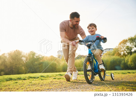 Bicycle, having fun. Happy father with son are on the field at summertime 131393426