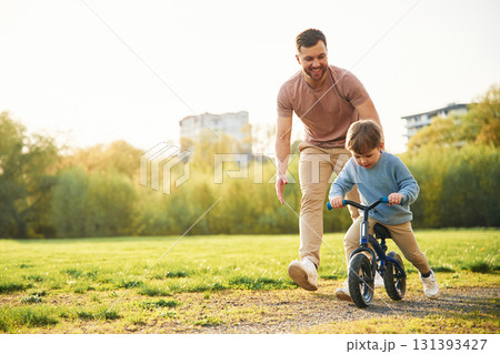 Bicycle, having fun. Happy father with son are on the field at summertime Bicycle, having fun. Happy father with son are on the field at summertime 131393427
