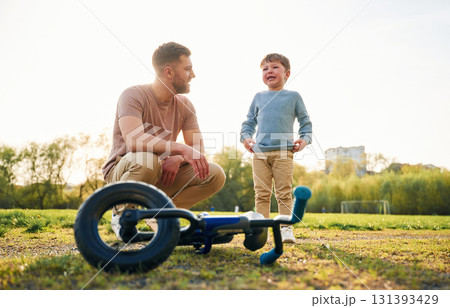 Little bicycle. Happy father with son are having fun on the field at summertime Little bicycle. Happy father with son are having fun on the field at summertime 131393429
