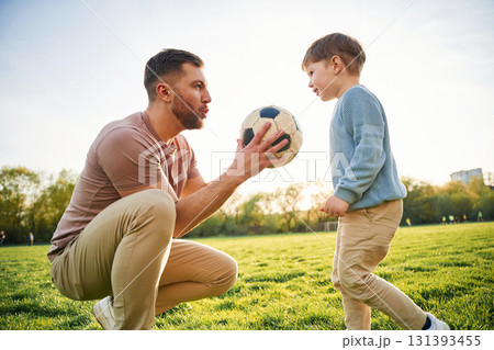 With soccer ball. Happy father with son are having fun on the field at summertime 131393455