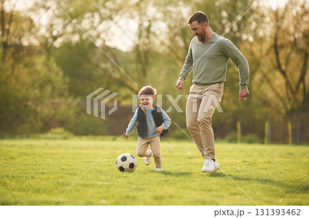 With soccer ball. Happy father with son are having fun on the field at summertime 131393462
