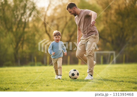 Learning to play soccer. Happy father with son are having fun on the field at summertime Learning to play soccer. Happy father with son are having fun on the field at summertime 131393468
