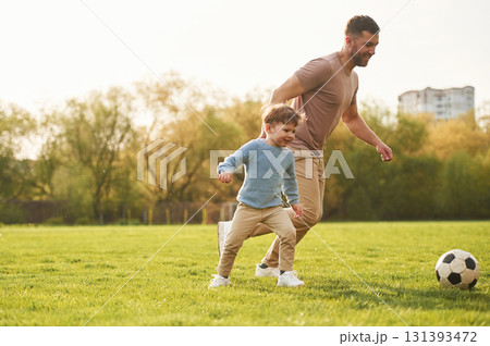 Teaching how to play a soccer. Happy father with son are having fun on the field at summertime Teaching how to play a soccer. Happy father with son are having fun on the field at summertime 131393472