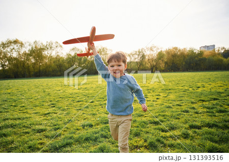 Running with toy plane. Cute happy little boy is on the field outdoors Running with toy plane. Cute happy little boy is on the field outdoors 131393516