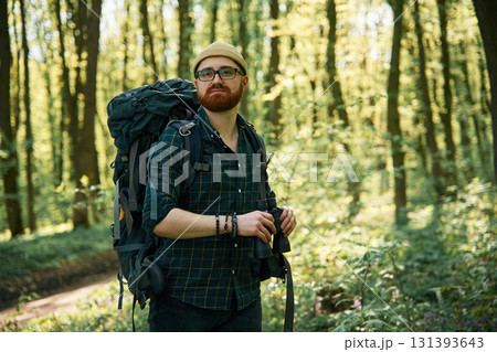Tourist with binoculars. Bearded man is in the forest at daytime Tourist with binoculars. Bearded man is in the forest at daytime 131393643