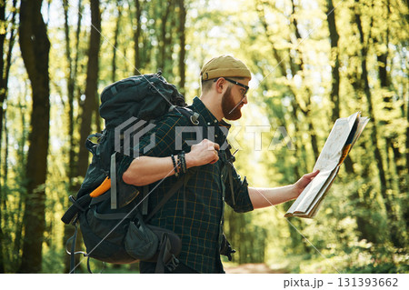 Big paper map. Bearded man is in the forest at daytime 131393662