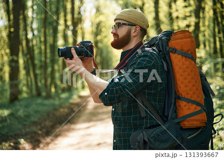 Photographer with camera. Bearded man is in the forest at daytime 131393667