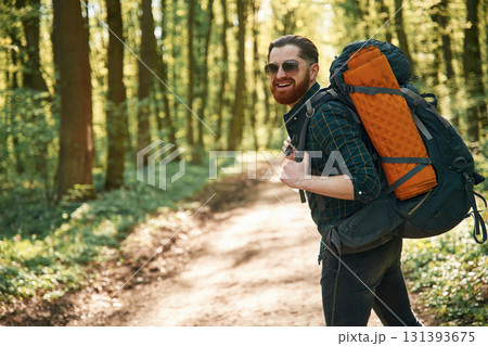With backpack. Bearded man is in the forest at daytime With backpack. Bearded man is in the forest at daytime 131393675