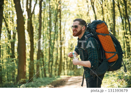 In glasses and with backpack. Bearded man is in the forest at daytime 131393679