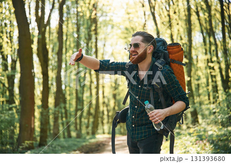 In glasses and with backpack. Bearded man is in the forest at daytime 131393680