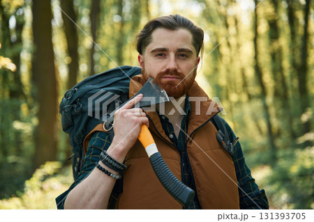 Shaving by using an axe. Bearded man is in the forest at daytime Shaving by using an axe. Bearded man is in the forest at daytime 131393705
