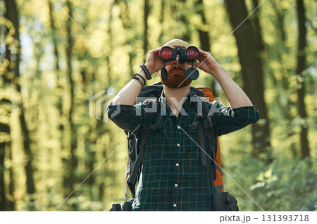 Discovering new place with binoculars. Bearded man is in the forest at daytime 131393718