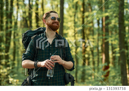In cool sunglasses. Bearded man is in the forest at daytime In cool sunglasses. Bearded man is in the forest at daytime 131393738