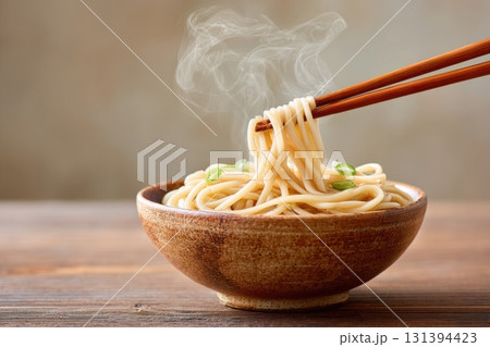 Soba noodles in rustic bowl with steam rising, captured in minimalist style, showcasing the warmth and simplicity of traditional Japanese cuisine with copy space 131394423