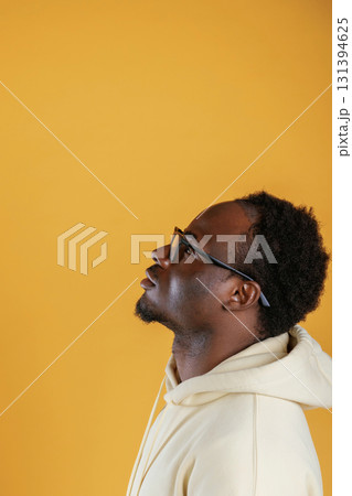 In glasses, looks to the copy space. Black guy is against yellow background In glasses, looks to the copy space. Black guy is against yellow background 131394625