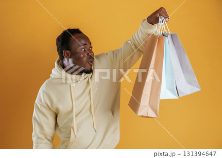 Crazy sales, with shopping bags. Black guy is against yellow background 131394647
