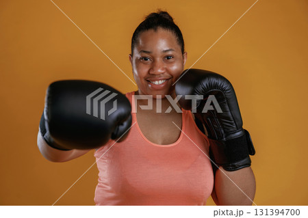 Boxer is ready to fight. African American woman is in the studio against yellow background 131394700