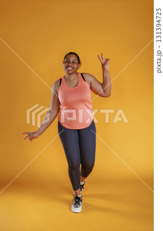 In fitness sportive clothes. African American woman is in the studio against yellow background In fitness sportive clothes. African American woman is in the studio against yellow background 131394725