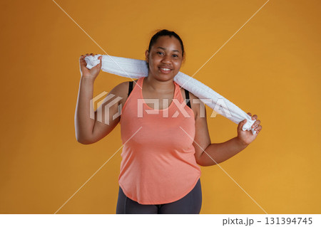 With white towel, after exercise. African American woman is in the studio against yellow background With white towel, after exercise. African American woman is in the studio against yellow background 131394745