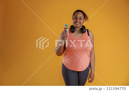 Bottle of water, break, standing with headphones on the neck. African American woman is in the studio 131394770