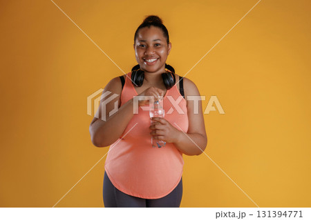 Bottle of water, break, standing with headphones on the neck. African American woman is in the studio 131394771