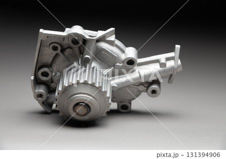 A new, shiny aluminum engine coolant pump on a gray gradient background. Contrast backlighting. A new, shiny aluminum engine coolant pump on a gray gradient background. Contrast backlighting. 131394906