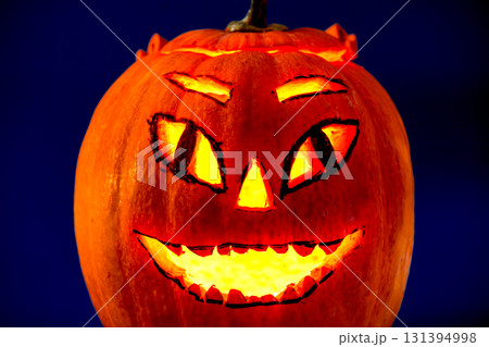Halloween pumpkin with candle light inside on a dark blue background 131394998