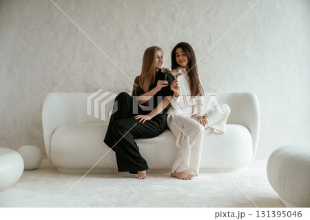 With drink, celebrating. Two happy young female best friends are indoors 131395046