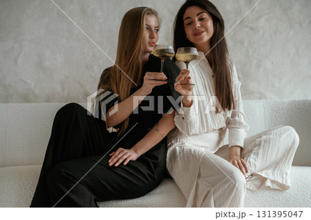 With drink, celebrating. Two happy young female best friends are indoors With drink, celebrating. Two happy young female best friends are indoors 131395047