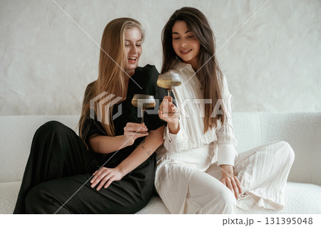 Event, with drinks, celebrating. Two happy young female best friends are indoors 131395048